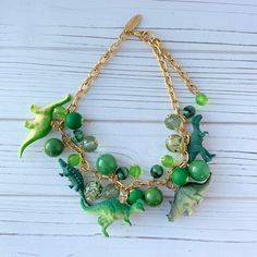 Another addition to our popular Iconic Dino Necklace Collection https://etsy.me/3rCeB7x that's been a best seller with Lenora Dame collectors for years! This totally quirky necklace filled with bauble charms and toy dinosaurs in a rich green jewel tone color palette makes a statement that says, you know how to keep your accessories game strong! Explore other color palettes such as pink https://etsy.me/3KpBRye, yellow and purple https://etsy.me/3rRg4XH found in this collection of dinosaur necklac Dinosaur Necklaces, Dino Necklace, Quirky Necklace, Toy Dinosaurs, Surprise Gifts For Her, Tone Color Palette, Jewel Tone Color Palette, Colourful Jewellery, Dinosaur Necklace