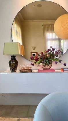 a mirror sitting on top of a white table next to a vase with flowers in it