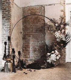 an arch with flowers and candles on the floor next to a brick wall that has been torn down