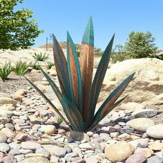 a metal plant sitting on top of a pile of rocks