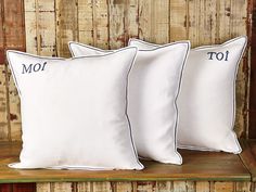 three white pillows sitting on top of a wooden shelf