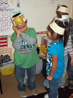 two children wearing paper hats in a classroom