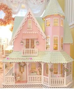 a pink doll house sitting on top of a white floor next to a window with curtains