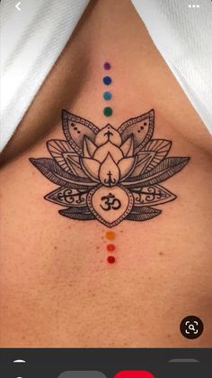 a woman's chest with a lotus tattoo on the top and seven chakras