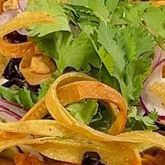 a salad with tortilla chips, lettuce and black olives on it