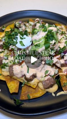 a black plate topped with nachos covered in toppings