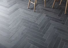 the floor is made up of grey herringbone tiles and wooden barstools with stools on each side