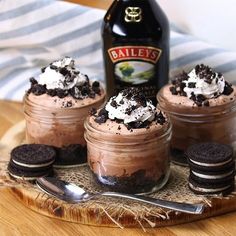 there are cookies and ice cream in jars on the table with a bottle of bailey's