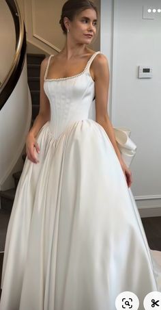 a woman in a white dress standing next to a stair case