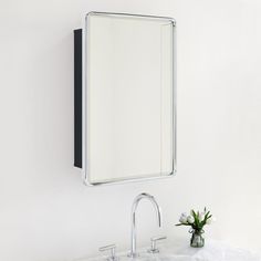 a bathroom sink sitting under a mirror next to a wall mounted faucet and a vase with flowers