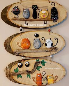 three wooden boats with cats painted on them hanging from the side, one has a tree branch in front of it