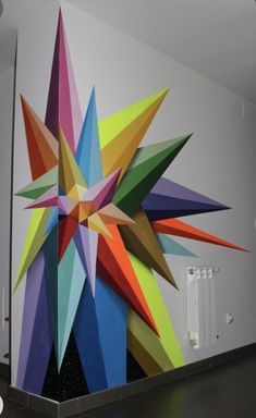 a large multicolored star painted on the side of a white wall next to a radiator