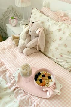 a teddy bear sitting on top of a bed next to a bowl of food