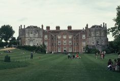 people sitting on the grass in front of a large building