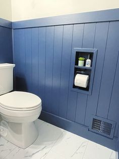 a white toilet sitting in a bathroom next to a blue wall