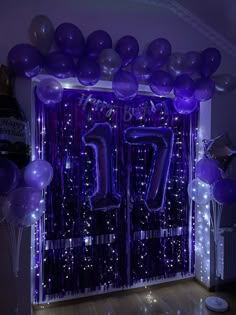 purple balloons and streamers decorate the entrance to a party with an illuminated number seventy