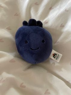 a blue stuffed animal with a smile on it's face sitting on a white sheet