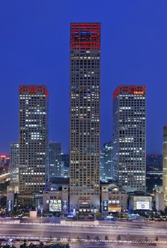 the city is lit up at night with red lights on it's skyscrapers