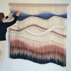 a woman is working on a wall hanging with beads and yarn in the shape of waves