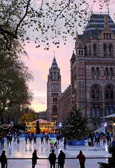 people skating on an ice rink in front of a large building