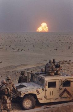 an image of soldiers in the desert with a vehicle and rocket behind them that is on fire