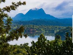 a lake surrounded by trees and mountains in the distance with a sign pointing to it