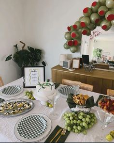 a table is set with plates, silverware and green balloons in the shape of a wreath