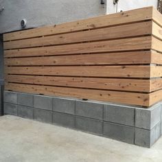 a large wooden bench sitting on top of a cement block next to a building with windows