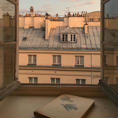 an open window with the view of rooftops and buildings from it's windows