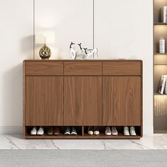 a wooden cabinet with shoes on it in a white room next to bookshelves