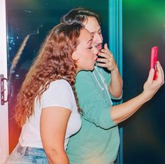 two women standing next to each other holding cell phones