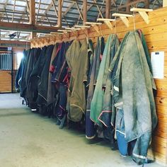 several jackets hanging up against a wall in a warehouse