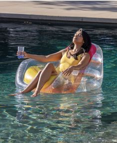 a woman sitting on an inflatable float floating in the water with a drink