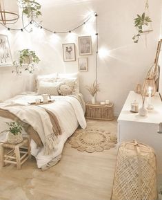 a bedroom with white walls and wooden flooring has plants on the wall above the bed