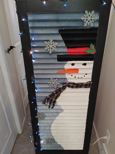 a snowman made out of shutters on the side of a door with christmas lights around it