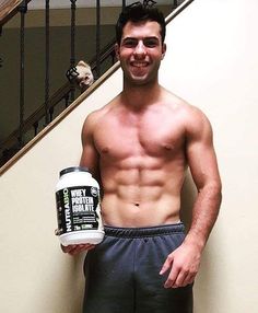 a man holding a can of whey protein while standing in front of some stairs