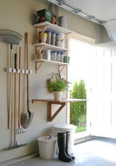 a shelf with gardening utensils and plants on it in front of a door