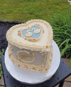 there is a cake shaped like a box with two swans on it and flowers in the shape of a heart