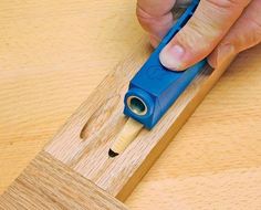 a person using a blue tool to cut wood