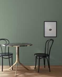 two chairs and a table against a green wall