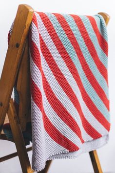 a red, white and blue blanket sitting on top of a wooden chair next to a ladder