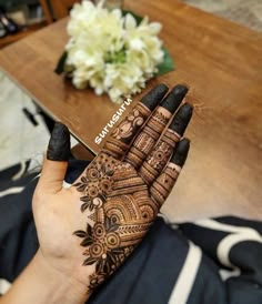 a woman's hand with henna on it and some flowers in the background