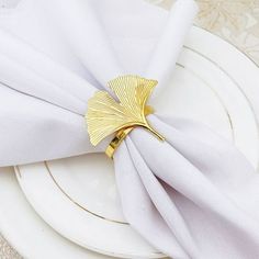 the napkins are folded on top of each other and have gold leaves attached to them