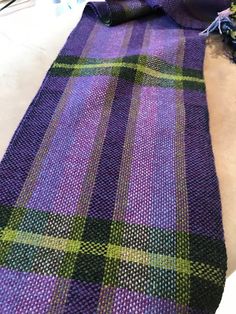 a purple and green plaid cloth laying on the floor