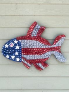 a fish made out of plastic beads on the side of a building with an american flag painted on it