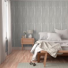 a white bed sitting in a bedroom next to a wooden dresser and lamp on top of a hard wood floor