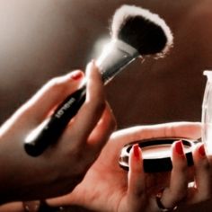 a woman holding a brush in her hand next to a cup with something on it