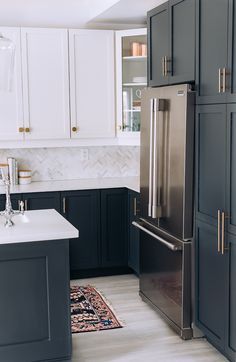 a kitchen with black cabinets and white counter tops, an area rug on the floor