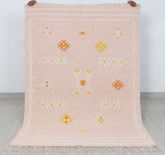 a pink rug with orange and white designs on it, hanging from the wall in front of