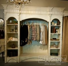 a closet with clothes hanging on the wall and a chandelier in the corner